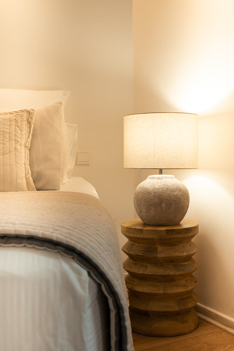 Le lit et sa lampe en bois, dans une lumière douce