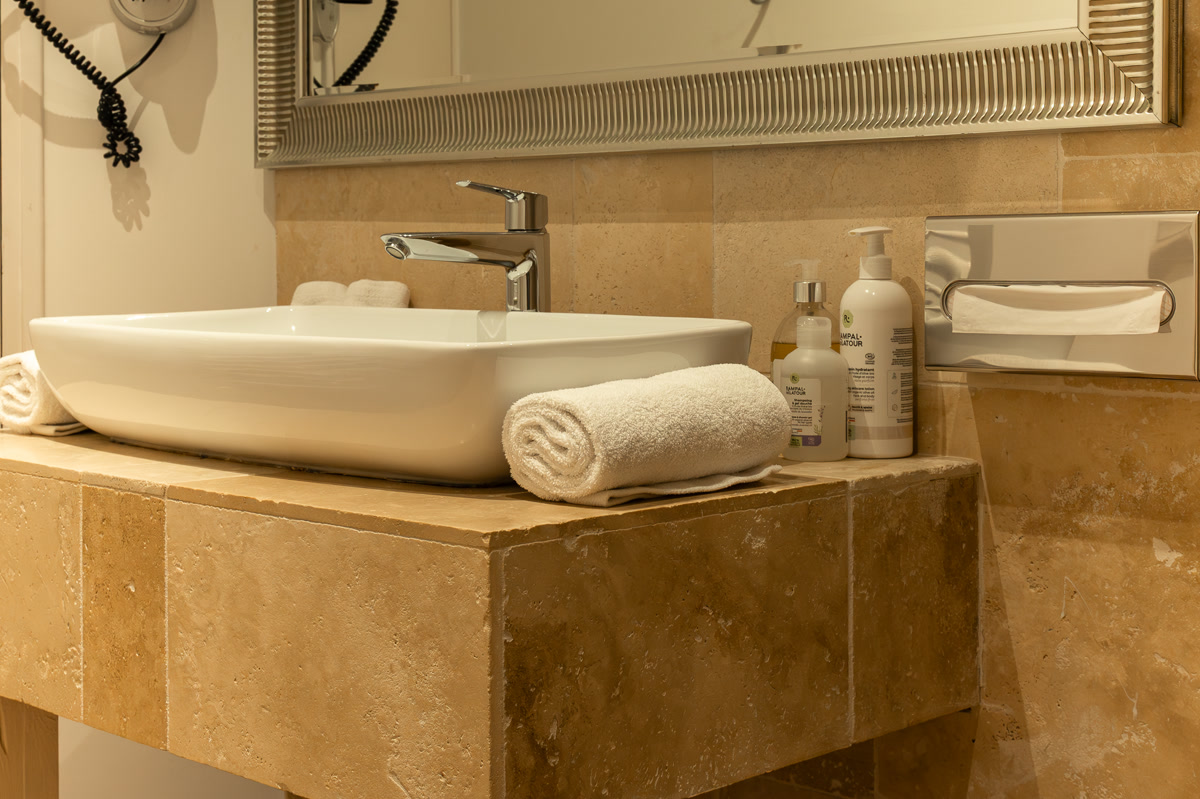 La salle de bain de La Calissanne : vasque en pierre, miroir et serviettes