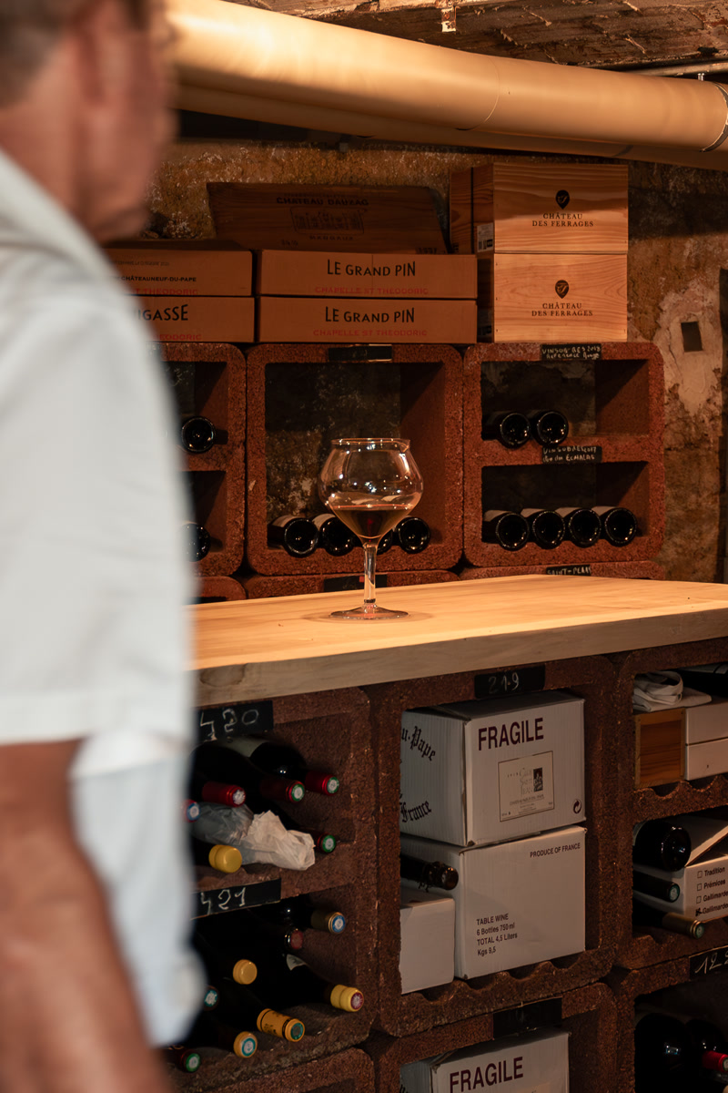 Alain dans sa cave, entre les casiers et les caisses des domaines