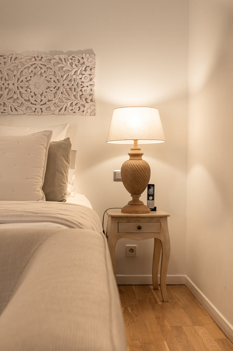 La lampe du chevet et le panneau de bois sculpté blanc au-dessus du lit