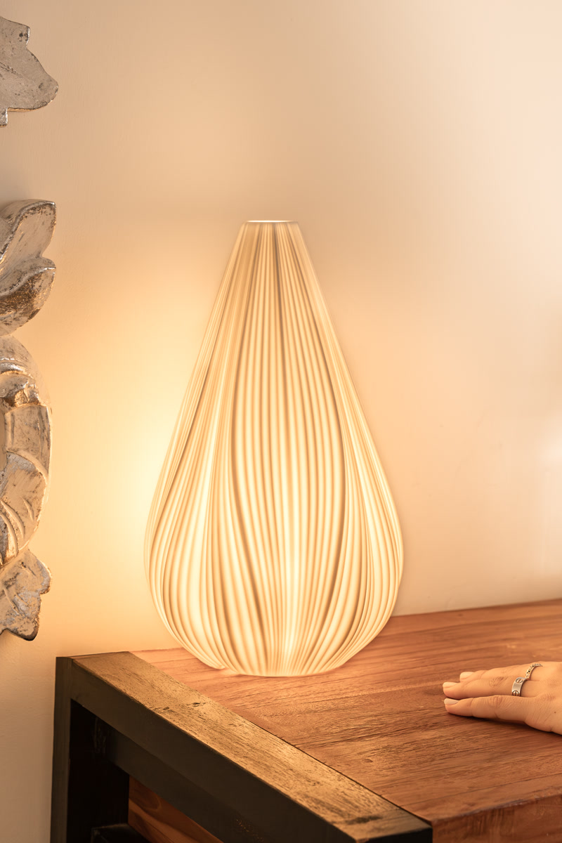 La lampe du chevet allumée, sa goutte de verre plissé