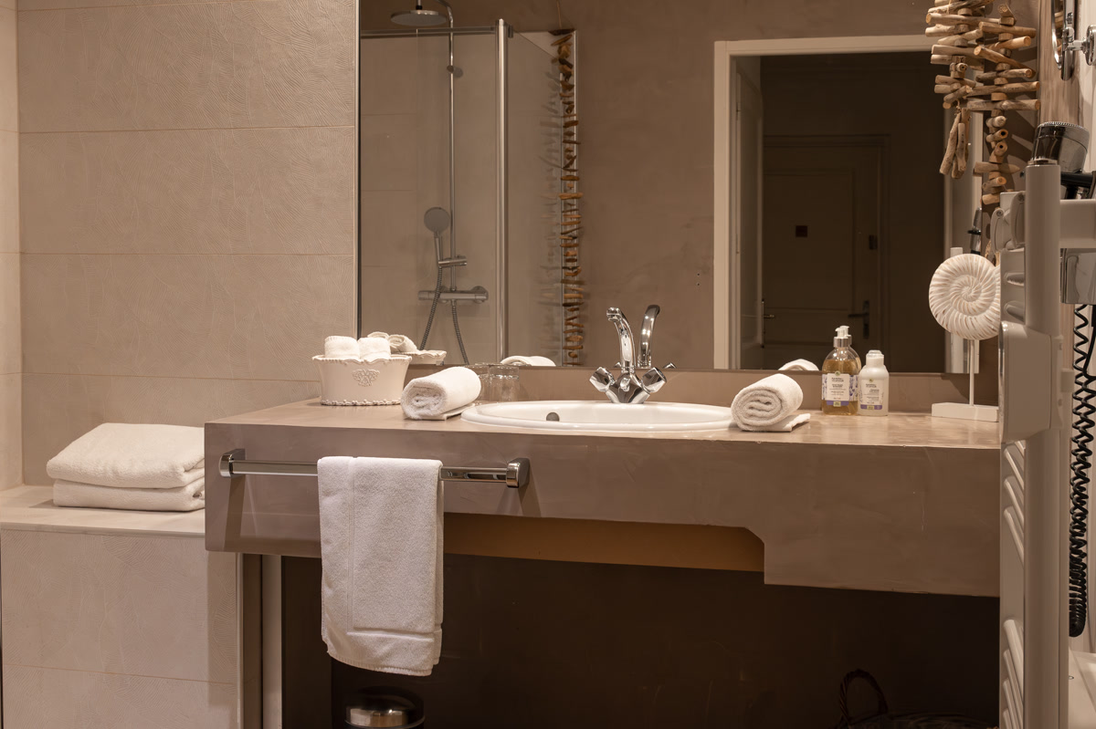 La salle de bain de La Paternel : la vasque, le miroir, et la douche de plain-pied au fond