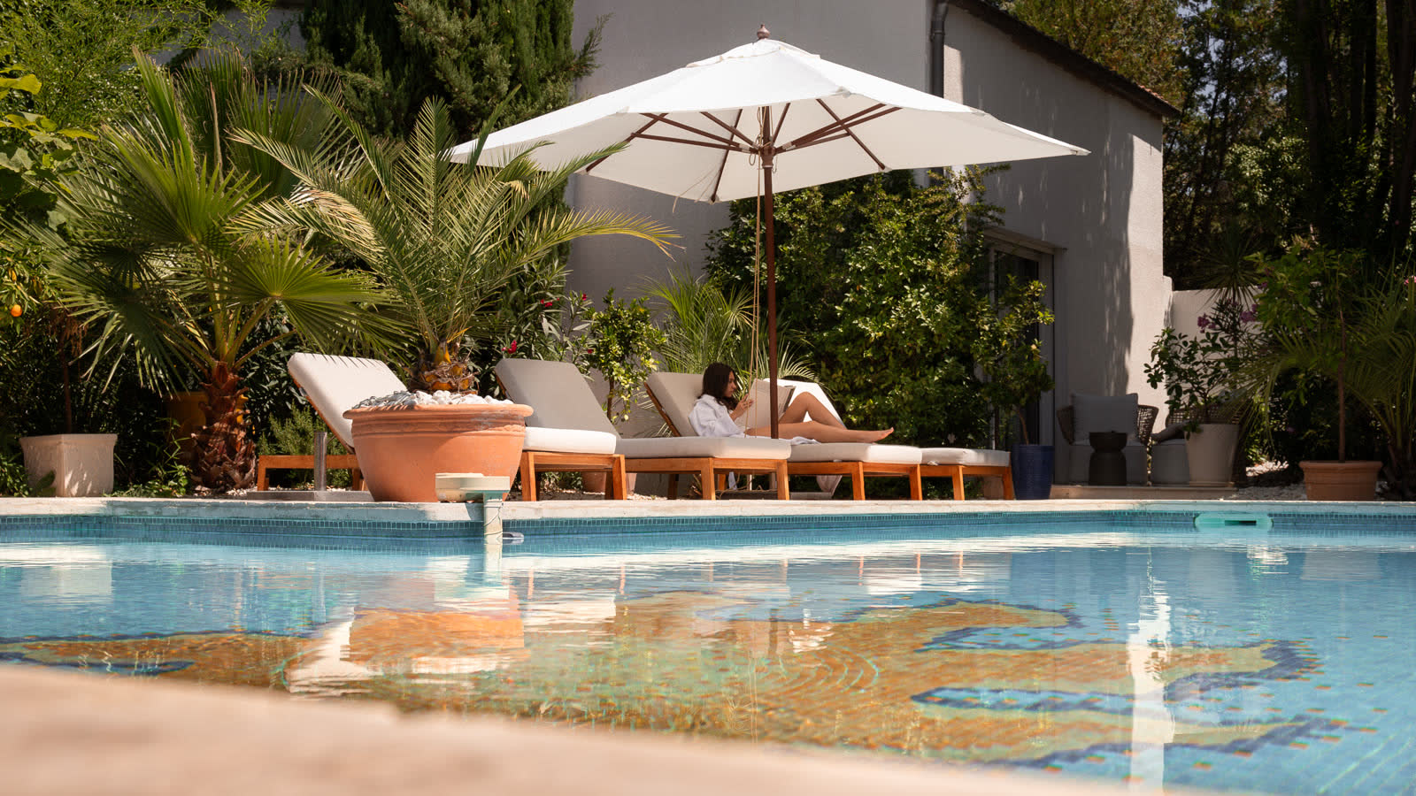 Lecture à l'ombre du parasol, au bord de la piscine