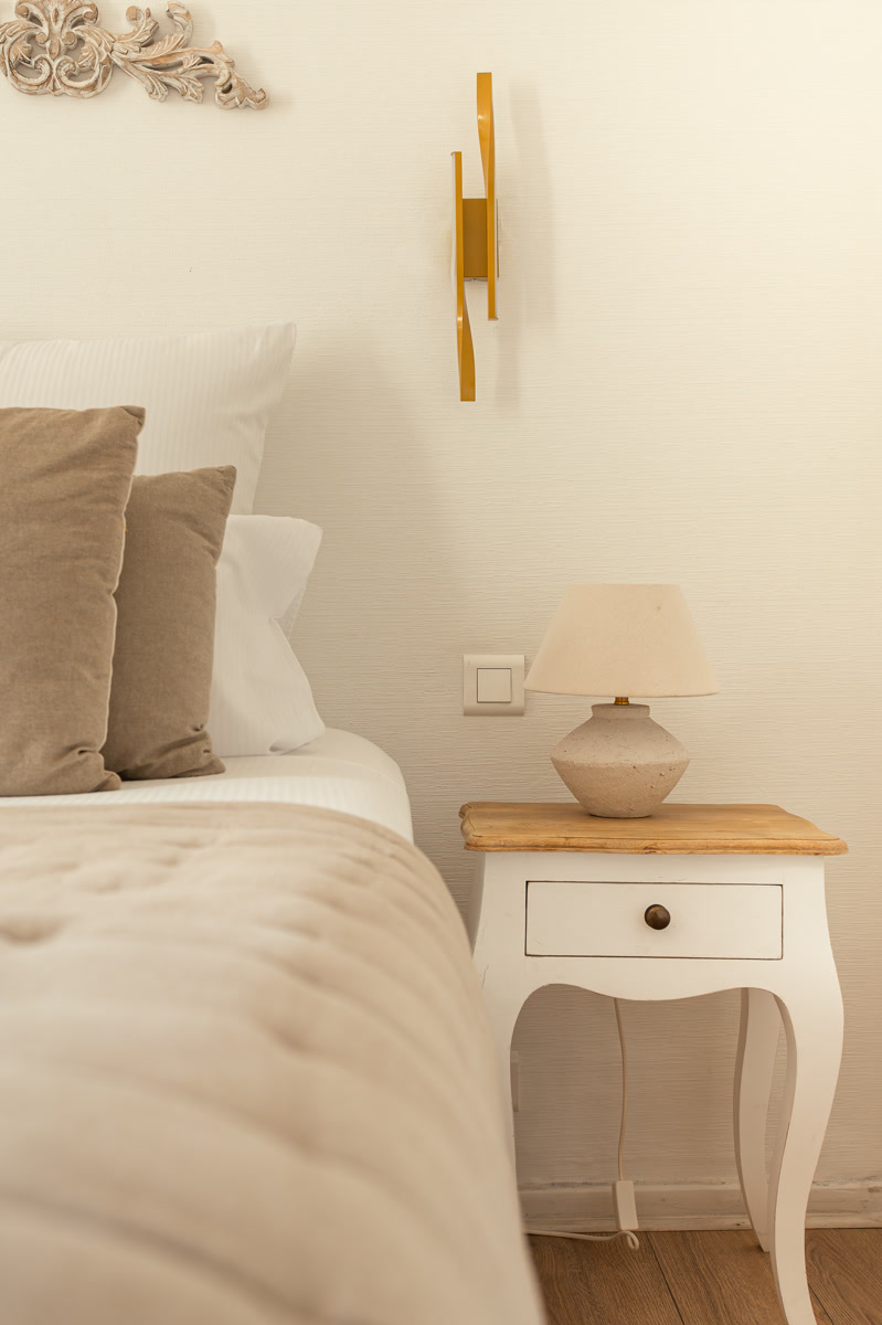 La lampe de pierre sur le chevet, au pied du lit