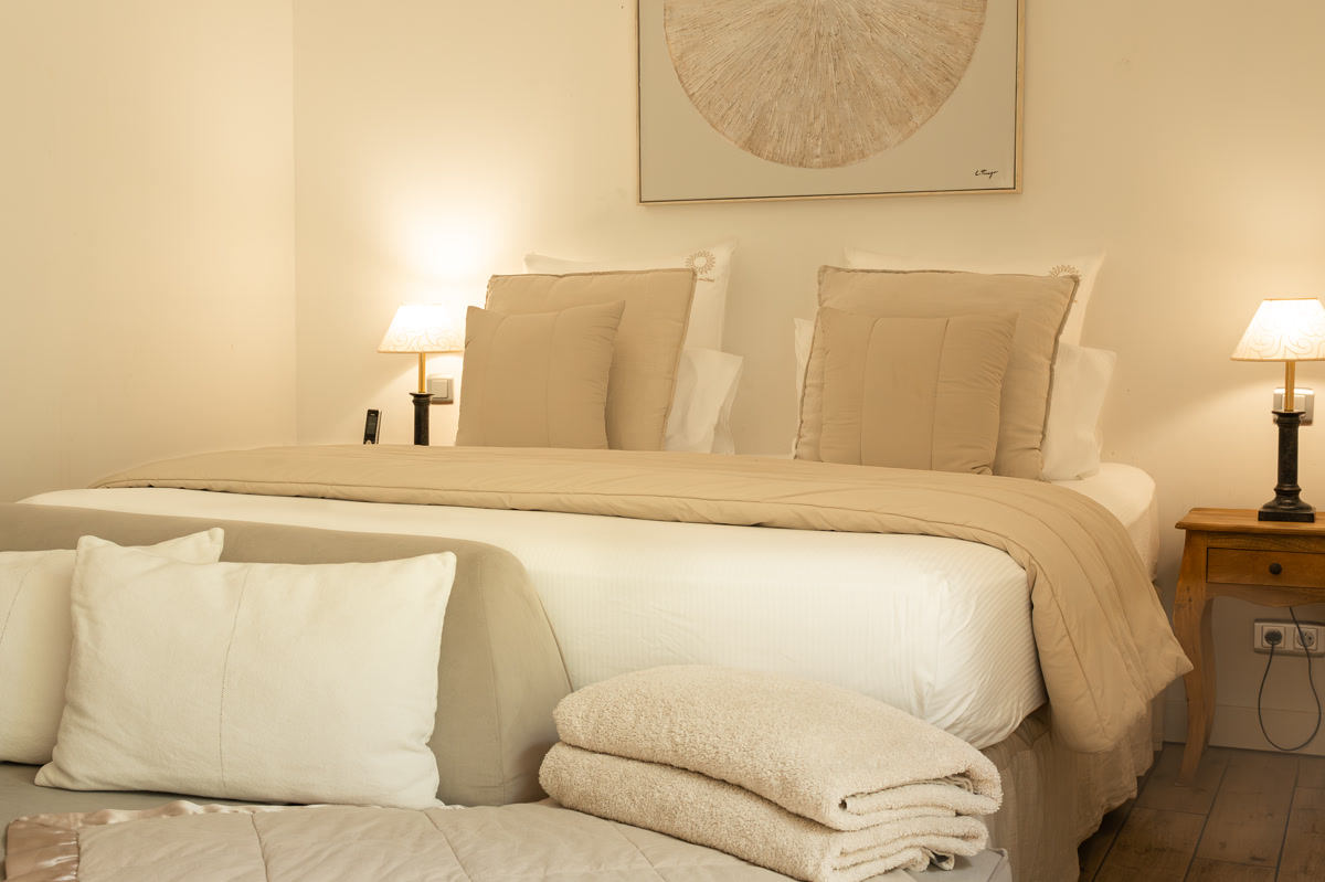 La chambre La Simone : le lit de 180, le plaid plié et le tableau rond au-dessus