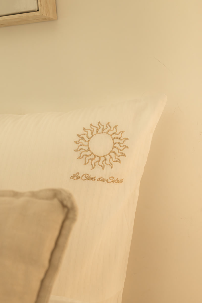 Le soleil du Clos brodé sur le coussin du lit